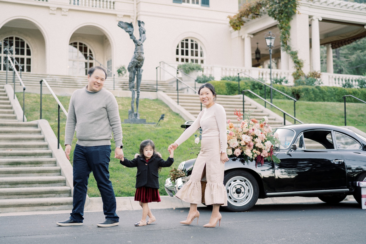 Family posing in front of a vintage Porsche